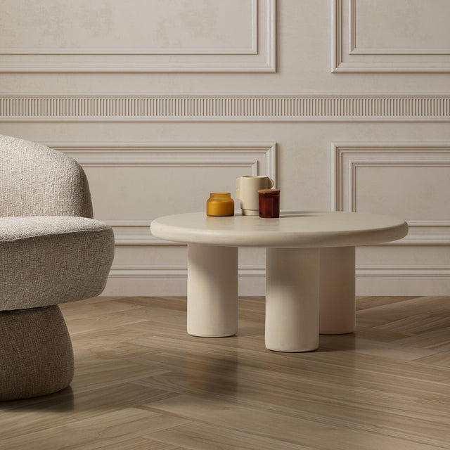 Mesa de centro redonda Iriel 80 cm Tres patas crema efecto cemento, en ambiente de salón
